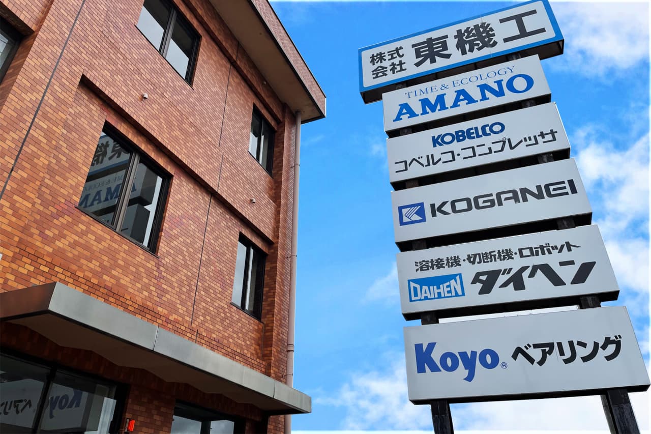 株式会社東機工・本社仙台営業所の入口前。看板に取扱いメーカーの名前が並ぶ